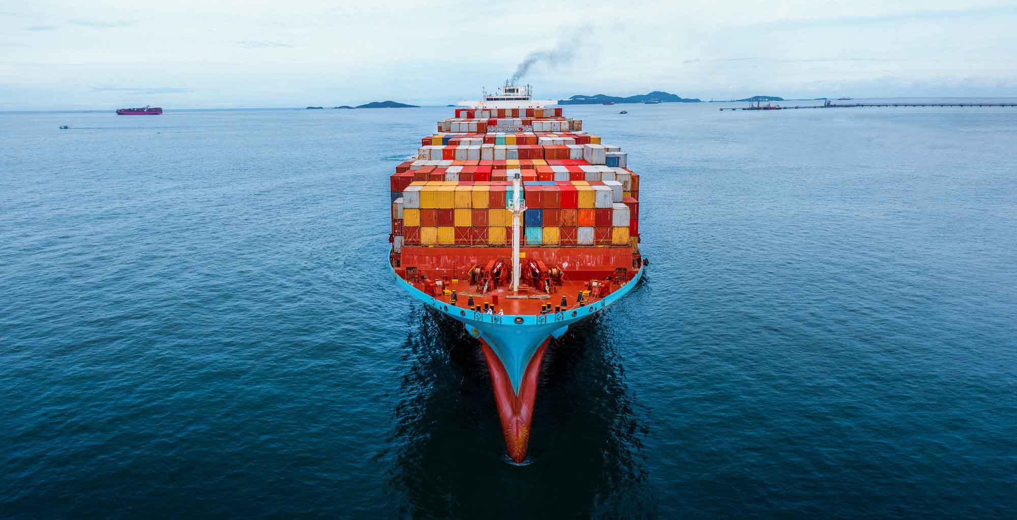 Aerial in front of cargo ship carrying container and running for export goods from cargo yard port to custom ocean concept freight shipping by ship .